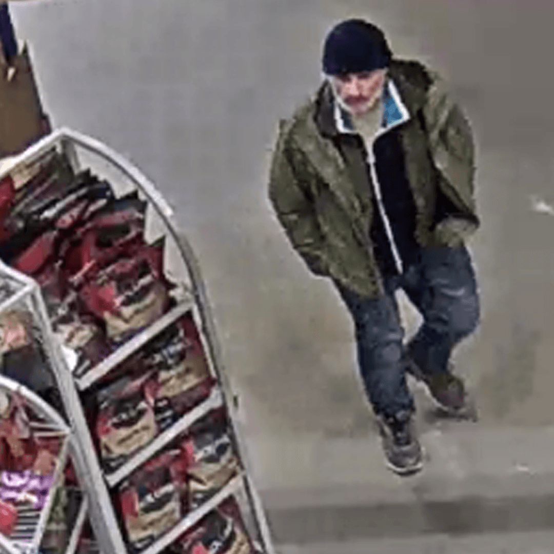 Store camera still of a person wearing a dark beanie and green jacket